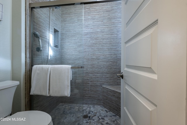 bathroom featuring toilet and a shower with shower door