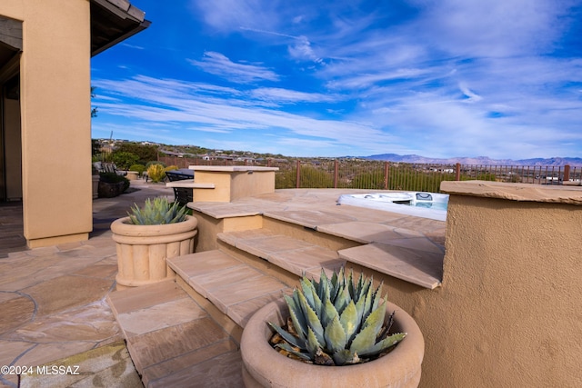 view of patio featuring a mountain view and a hot tub