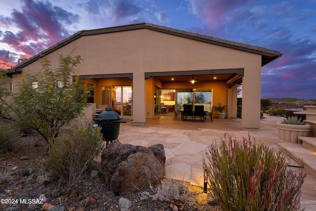 back house at dusk featuring a patio area