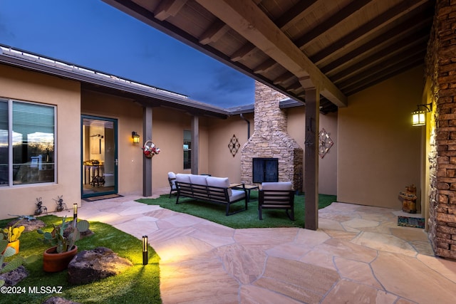 patio terrace at dusk featuring an outdoor living space with a fireplace