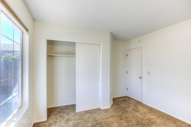 unfurnished bedroom with a closet and light colored carpet