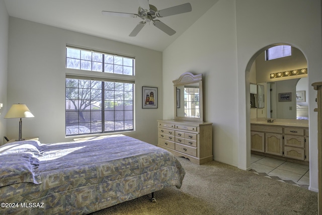 bedroom with light carpet, high vaulted ceiling, sink, ensuite bath, and ceiling fan