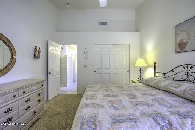 bedroom with light carpet, a towering ceiling, a closet, and ceiling fan