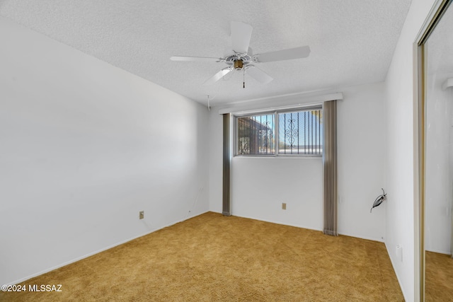 spare room with ceiling fan, a textured ceiling, and carpet flooring