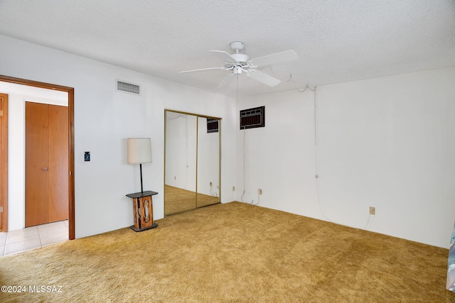 unfurnished bedroom featuring light carpet, ceiling fan, and a textured ceiling