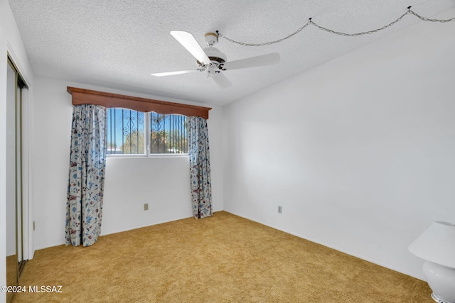 carpeted empty room with ceiling fan and a textured ceiling