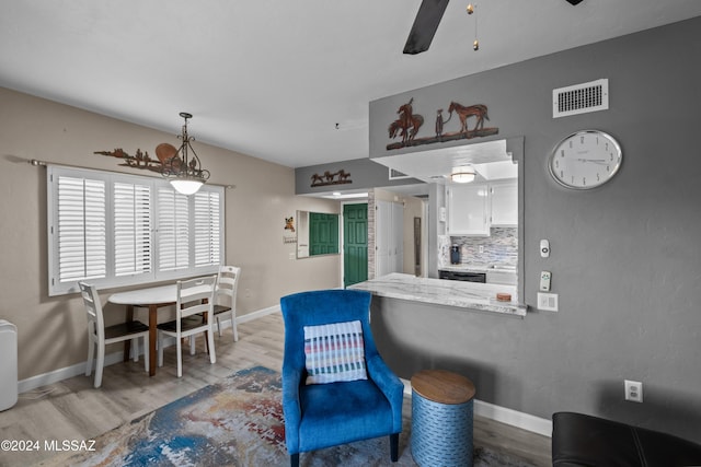 kitchen featuring tasteful backsplash, ceiling fan, white cabinets, light hardwood / wood-style floors, and hanging light fixtures