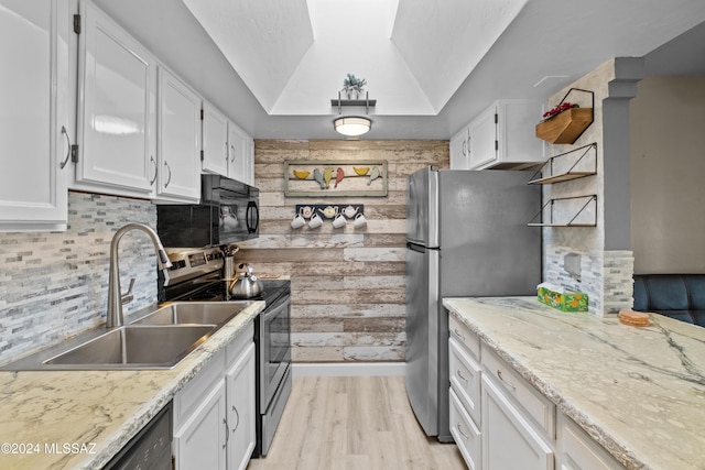 kitchen featuring appliances with stainless steel finishes, backsplash, vaulted ceiling, sink, and white cabinetry