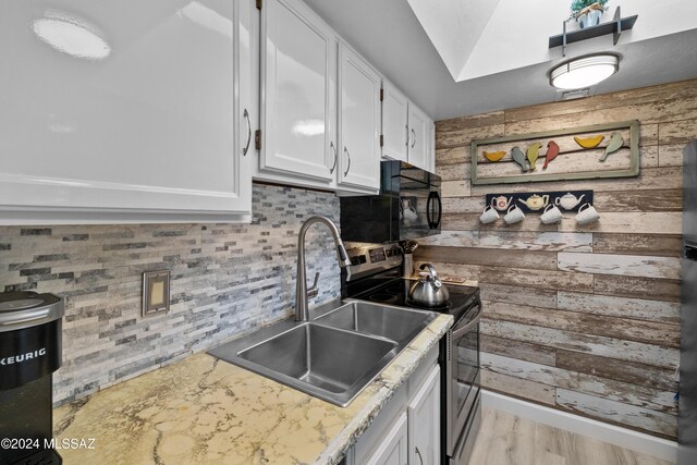 kitchen featuring white cabinetry, sink, light hardwood / wood-style floors, decorative backsplash, and stainless steel range with electric cooktop