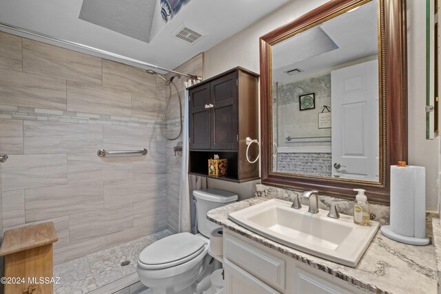 bathroom featuring a tile shower, vanity, and toilet