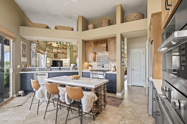 kitchen with gray cabinetry, a breakfast bar, light tile patterned floors, appliances with stainless steel finishes, and custom range hood