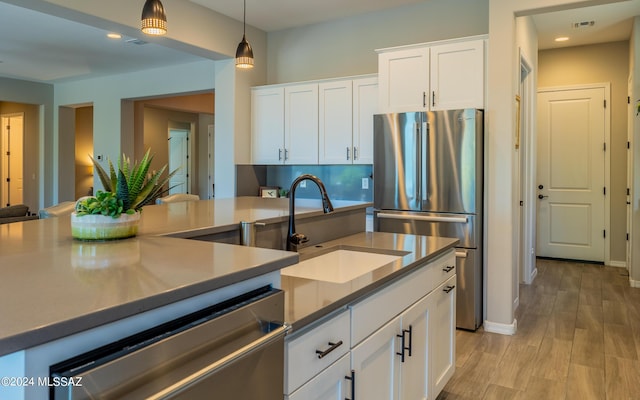 kitchen featuring white cabinetry, pendant lighting, stainless steel appliances, and sink