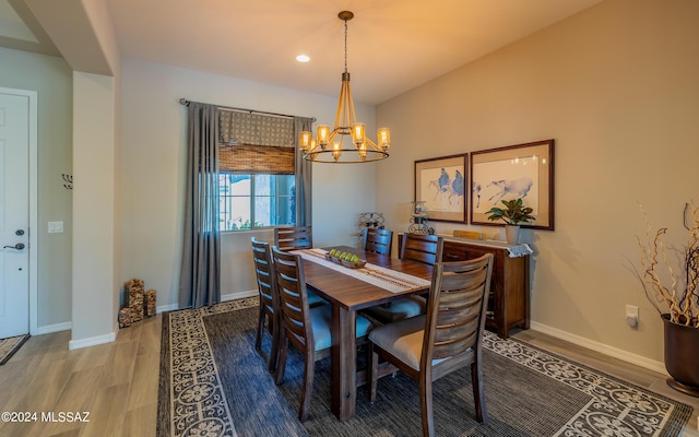 dining space with wood-type flooring and an inviting chandelier