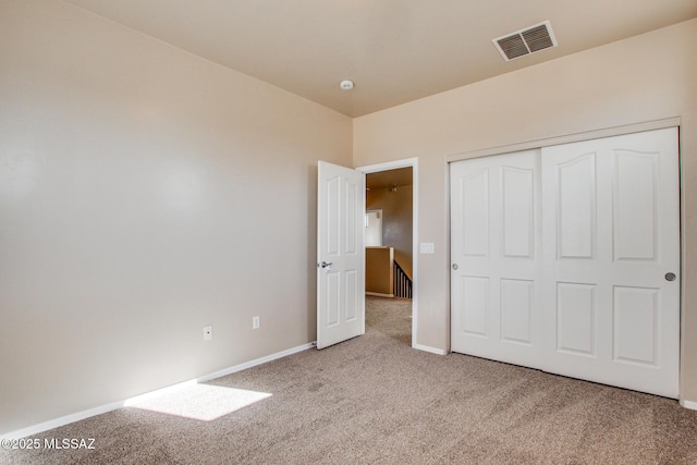 unfurnished bedroom with light carpet and a closet