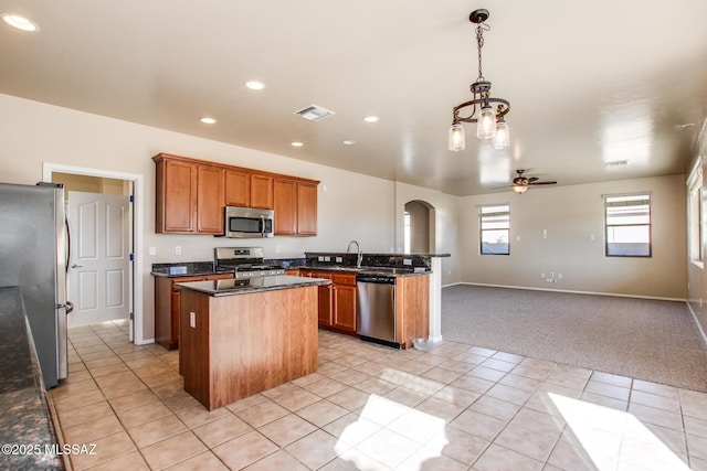 kitchen featuring pendant lighting, a center island, light carpet, stainless steel appliances, and ceiling fan