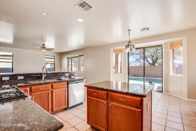 kitchen featuring a kitchen island, stainless steel dishwasher, sink, light tile patterned floors, and ceiling fan with notable chandelier