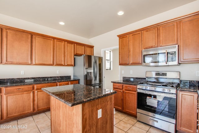 kitchen featuring dark stone countertops, light tile patterned floors, appliances with stainless steel finishes, and a kitchen island