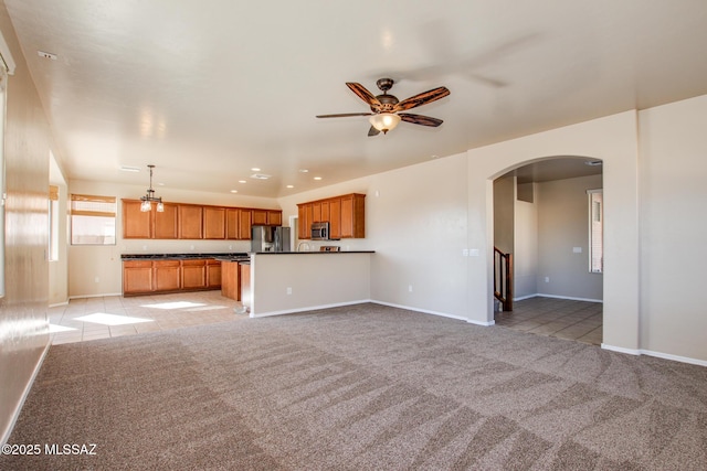 unfurnished living room with light carpet and ceiling fan with notable chandelier