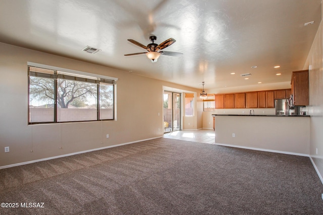 unfurnished living room with light carpet, ceiling fan, and sink