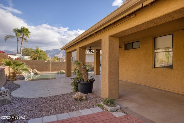 view of patio with a mountain view, a fenced in pool, and ceiling fan