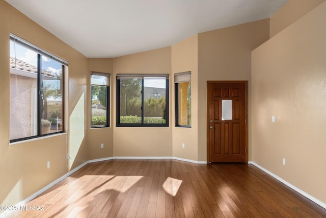 spare room featuring hardwood / wood-style floors and vaulted ceiling