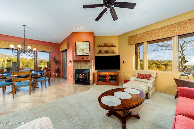 tiled living room with a tile fireplace and ceiling fan with notable chandelier