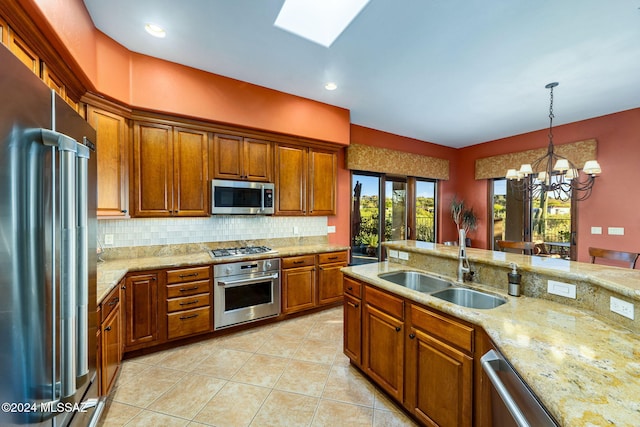 kitchen featuring sink, light stone counters, a notable chandelier, decorative light fixtures, and appliances with stainless steel finishes