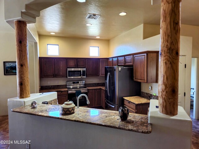 kitchen featuring stone counters, stainless steel appliances, dark tile patterned floors, and sink