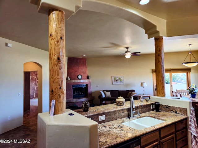 kitchen with ceiling fan, sink, hanging light fixtures, stainless steel dishwasher, and a fireplace