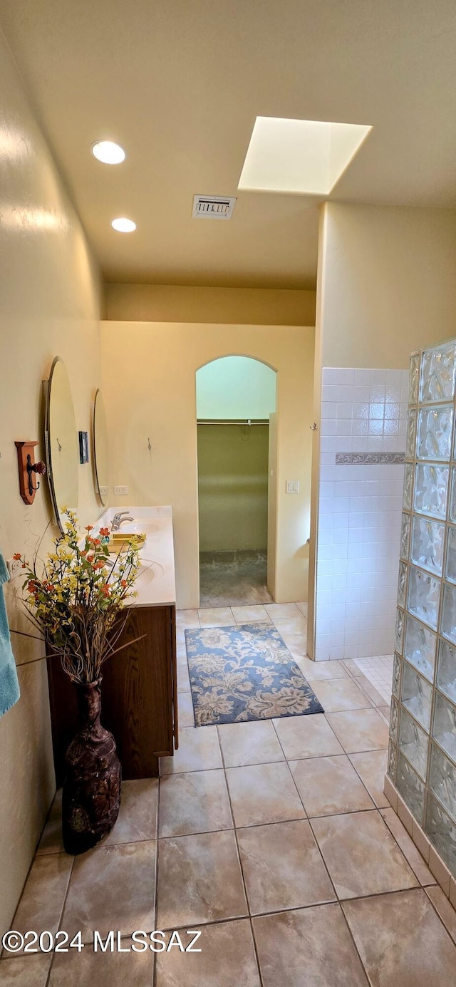 bathroom featuring tile patterned floors, a skylight, a shower, and vanity