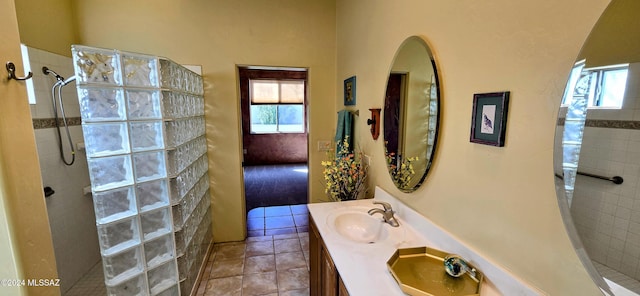 bathroom featuring a tile shower, tile patterned flooring, and vanity