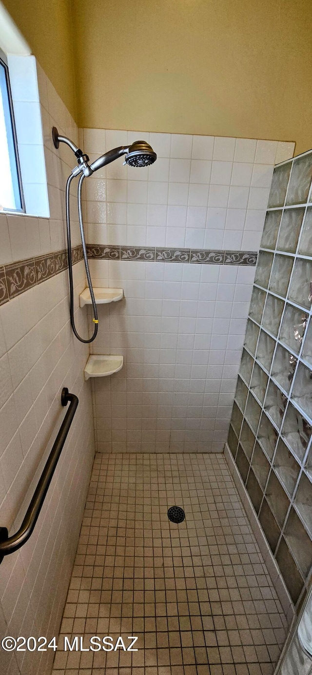 bathroom featuring tiled shower and tile walls