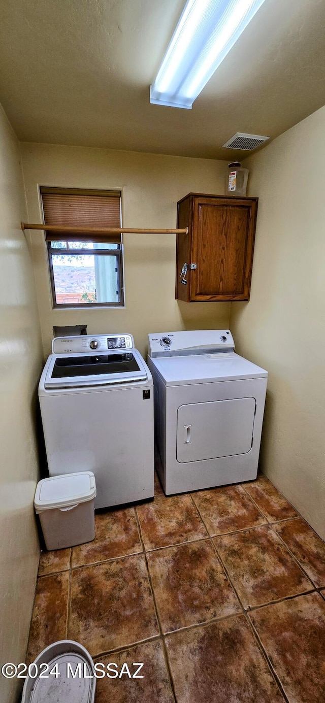 washroom featuring cabinets, dark tile patterned flooring, and washer and dryer