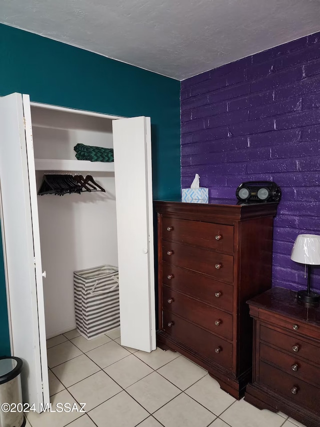 tiled bedroom with brick wall and a closet