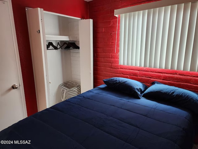 bedroom featuring a closet and brick wall