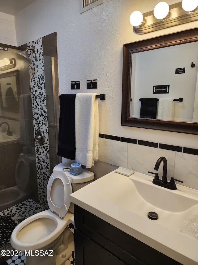 bathroom featuring toilet, a tile shower, tile walls, and vanity