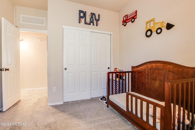 bedroom with carpet flooring, a crib, and a closet