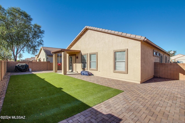 back of property featuring a lawn and a patio area