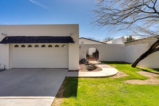 view of front of property with a garage, concrete driveway, a front lawn, and stucco siding