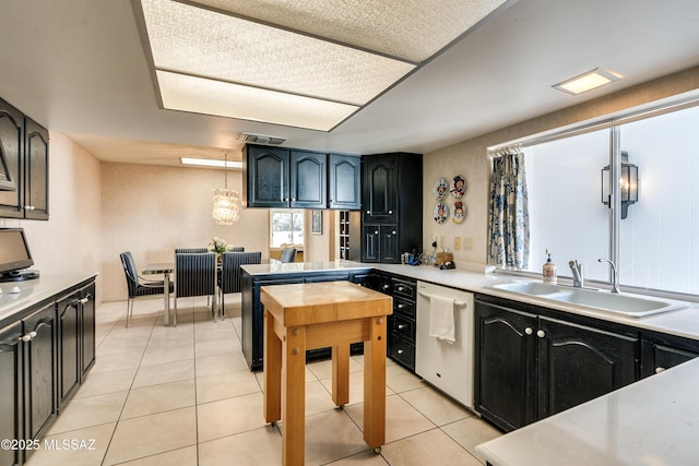 kitchen featuring light tile patterned floors, dishwasher, light countertops, pendant lighting, and a sink