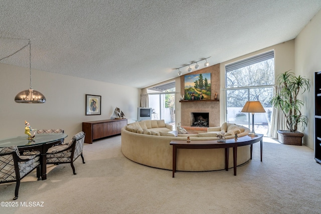 living room with a fireplace, light colored carpet, vaulted ceiling, a textured ceiling, and track lighting