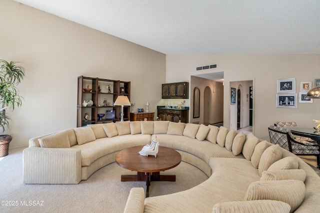 living area featuring lofted ceiling, visible vents, and light colored carpet