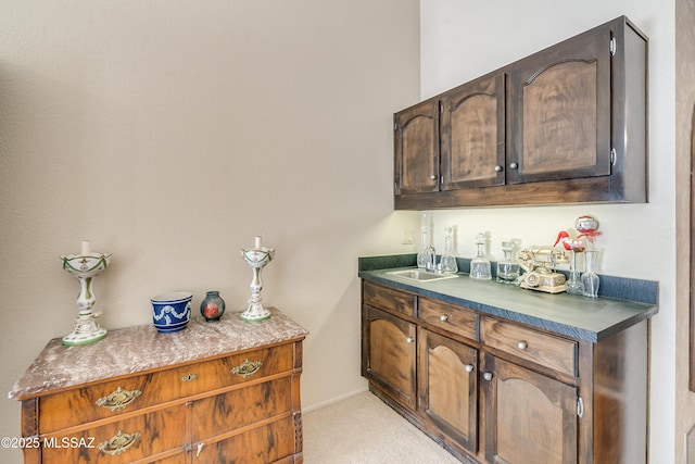 bar featuring light carpet, a sink, and baseboards