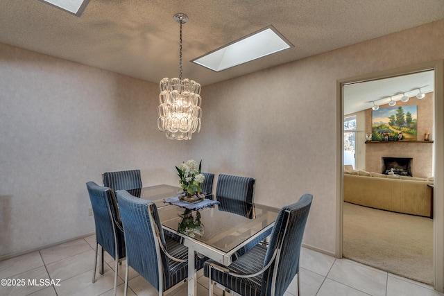 tiled dining space with a skylight, a fireplace, a chandelier, and a textured ceiling