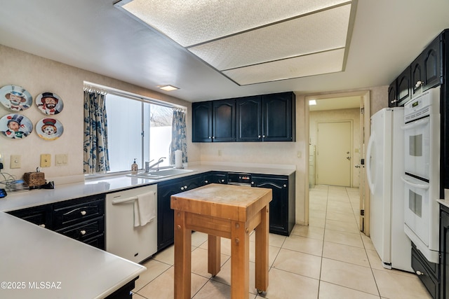 kitchen featuring white appliances, light countertops, a sink, and light tile patterned floors