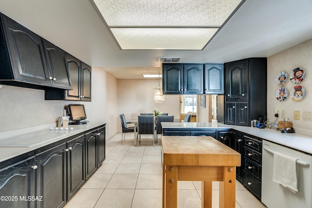 kitchen featuring white dishwasher, light tile patterned flooring, visible vents, light countertops, and dark cabinetry