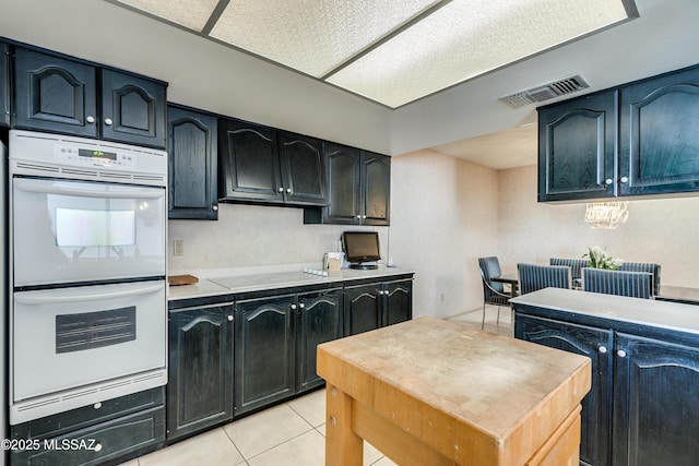 kitchen with light tile patterned floors, light countertops, white appliances, and visible vents