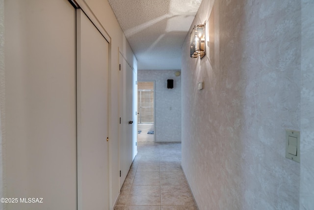 corridor featuring light tile patterned floors and a textured ceiling