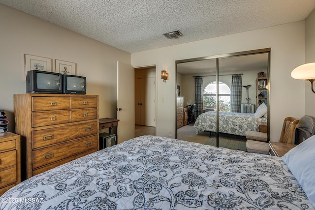 bedroom with a textured ceiling, a closet, and visible vents