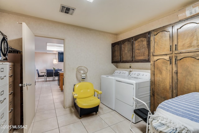 laundry area with light tile patterned floors, cabinet space, visible vents, and washer and dryer